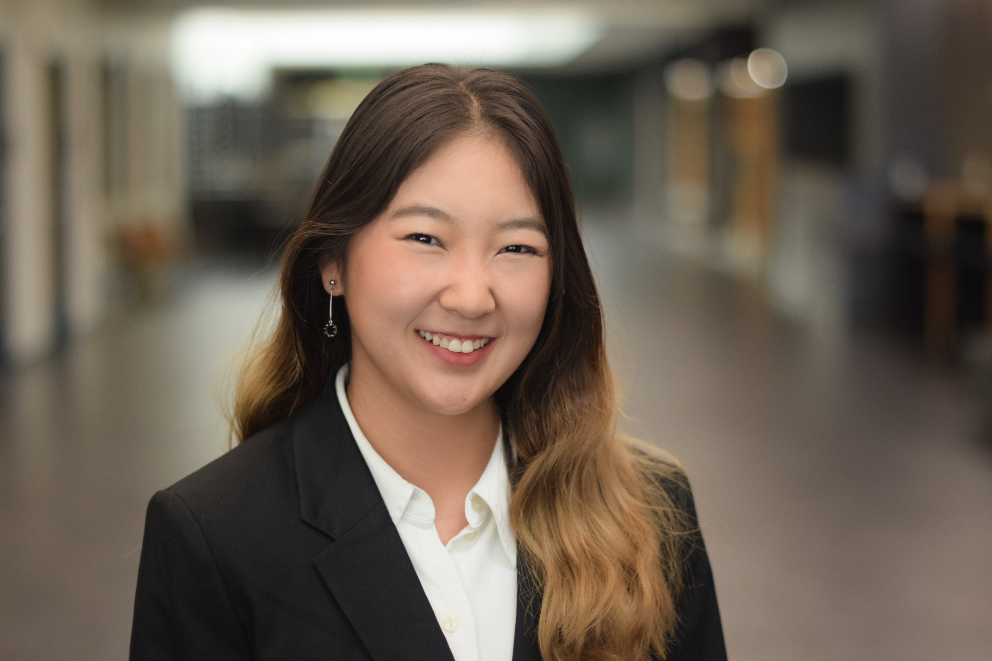 Head-and-shoulders portrait of Dangkamol Wongthanaroj standing indoors, wearing a dark blazer over a white collared shirt